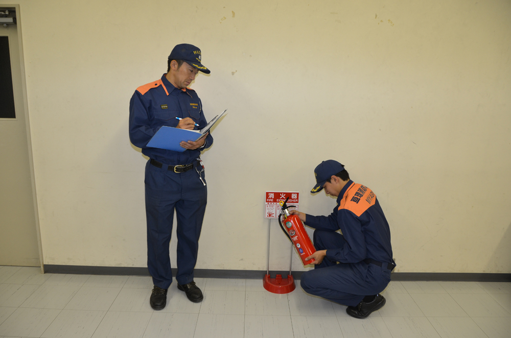 2人で消火器の点検を行う消防士の写真