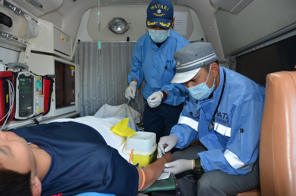 救急車の中で応急処置(点滴)の訓練を行う消防士の写真