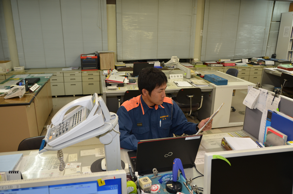 パソコンに向かい資料を見ながら書類作成を行う消防士の写真