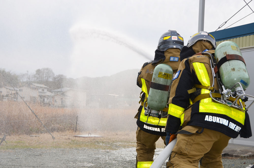 ホースを持ち消火訓練を行う消防士の写真