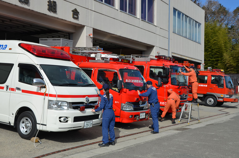 消防車や救急車を綺麗に掃除する消防士達の写真