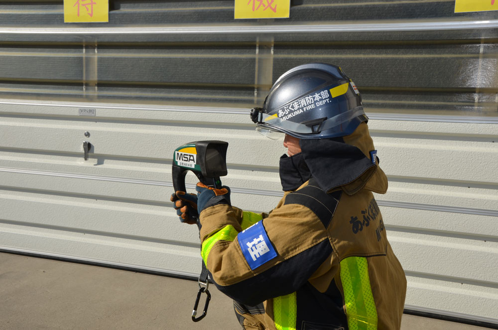 熱画像直視装置を使用した写真（消防士が両手で装置を握り画面を見ている）